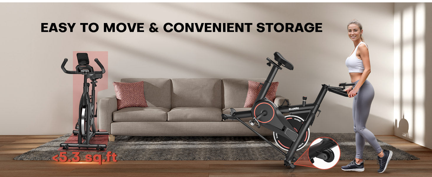 Motionscykel med en kvinna stående bredvid, placerad på ett trägolv i en vardagsrumsmiljö.